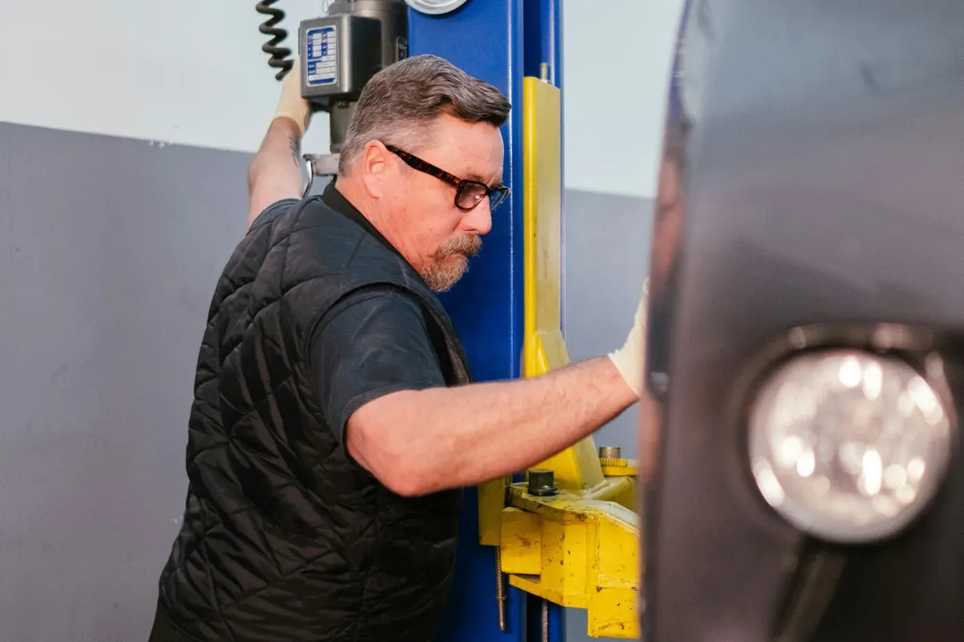 A mechanic raising a car on a two-post lift