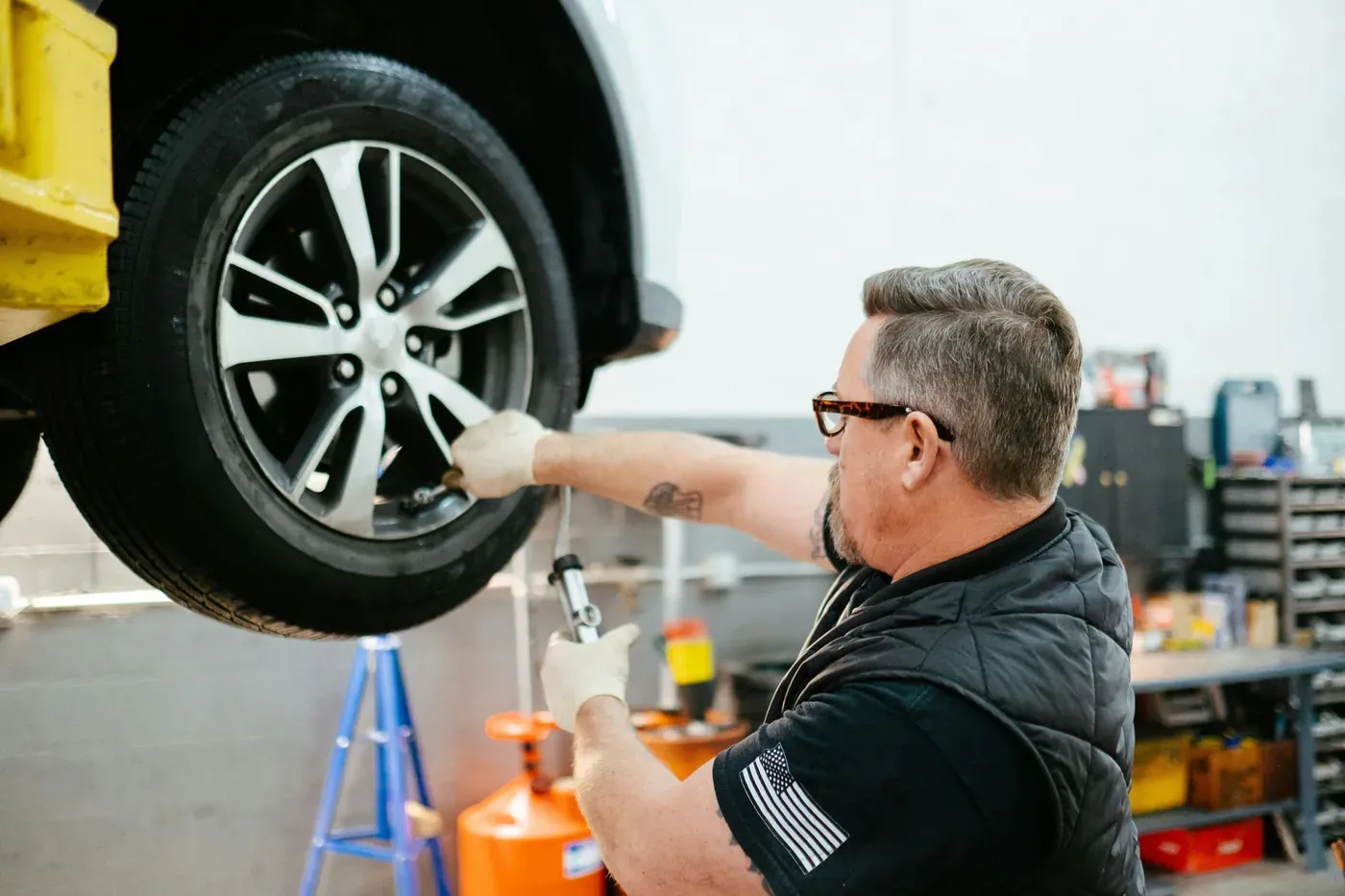 A mechanic torquing a wheel on a lifted car
